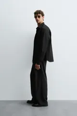 Camisa negra de manga larga con cuello italiano y cierre frontal de botonadura. Presenta un tejido con estructura de fácil cuidado.