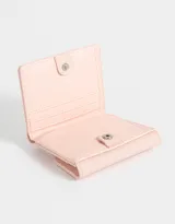 Billetera color rosa claro de cuerina engomada con solapa y tag en relieve con la frase "Tres Charmant". Tiene compartimentos para tarjetas y billetes.