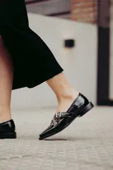 Chatitas de cuero con estampado animal print, con dos tiras cruzadas sobre el empeine y hebillas metálicas.