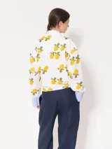 Camisa blanca de poplin con bordado de limones, jareta en la cintura con lazo ajustable, broches dorados, vivos blancos y puños en poplin rayado con ajuste mediante ojal y botón forrado.