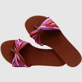 Sandalias Havaianas You St Tropez con base marrón y tira de tela estampada con rayas de colores y nudo decorativo.