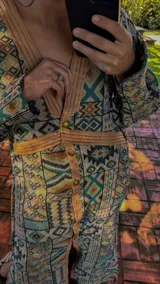 Vestido tipo abrigo con estampado geométrico en tonos azul, marrón y verde, con cuello en V, mangas abullonadas y cierre frontal con botones.