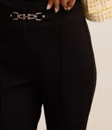 Pantalón flare de punto roma color beige, con detalle metálico en la cintura y cierre frontal.