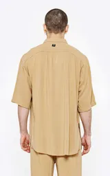 Camisa beige de lino con mangas 3/4, corte oversize y cuello clásico.