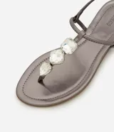 Sandalia plana dorada con tiras finas y aplicación de pedrería.