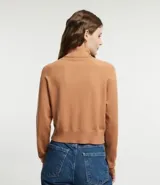 Blusa de punto color blanco, con cuello alto, manga larga y diseño liso.