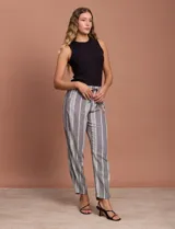 Pantalón largo de lino y rayón a rayas verticales grises y blancas. Tiene pretina elastizada con lazo de ajuste, bolsillos delanteros y traseros.