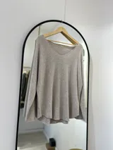 Sweater beige de tejido de punto, con escote en pico y corte recto.
