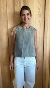 Chaleco gris con cuello redondo y sisas amplias. Presenta costuras verticales en el frente y bolsillos de parche a la altura del pecho.