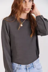 Blusa color beige de manga larga con detalles en los puños y corte ligeramente ajustado.