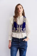 Chaleco azul de terciopelo con escote en U, bordados dorados con apliques de piedras, forro de jacquard y cierre frontal con ganchos invisibles.
