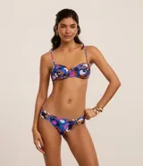Bikini con corpiño con aro y bombacha con laterales drapeados, con estampado floral en tonos azules, violetas, naranjas y blancos.