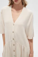 Vestido corto color crema, de corte holgado, con cuello en V y botones frontales.