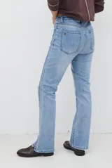 Jean de corte semi oxford con tiro medio, confeccionado en denim de lavado claro. Presenta costuras verticales decorativas en el frente y un detalle de costura en la botamanga que amplía la silueta.