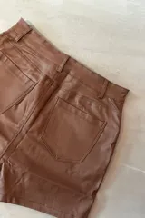 Short pollera negro de simil cuero, con cierre frontal y calce ajustado.