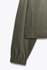 Cazadora bomber verde militar con capucha, cierre frontal con cremallera y bolsillos delanteros.