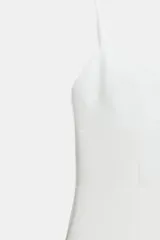 Mono corto blanco, con escote redondo, tirantes finos ajustables y abertura frontal.