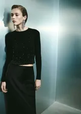Jersey negro de punto fino con strass, cuello redondo y manga larga.