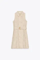 Vestido corto color beige con bordados florales perforados, cuello solapa, sin mangas, cinturón de tela con hebilla redonda y cierre frontal con botones.