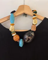Collar corto con cuentas de diferentes materiales y colores: turquesa, naranja, dorado, marrón y negro.