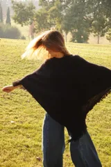 Poncho tejido en lana merino color crudo, con cuello alto y etiqueta de cuero con logo en la espalda.