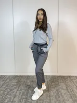 Pantalón gris con estampado de espiga, corte recto, cintura elastizada con lazo negro y bolsillos laterales.
