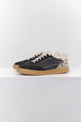 Zapatillas deportivas plateadas con detalles en gamuza gris, cordones blancos y suela color caramelo.