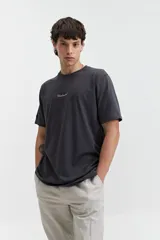 Remera color crema de manga corta con estampado de águilas y texto distorsionado en la espalda. Corte regular.