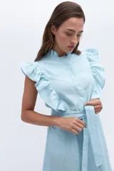 Vestido celeste de lino, corte a la rodilla, con cuello fruncido, volados en los hombros y lazo en la cintura.