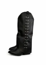 Botas negras de caña alta con punta en pico y tacón bajo. Presentan una hilera de ojales metálicos decorativos a lo largo de la caña.