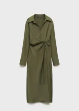 Vestido camisero midi color verde oliva, con cuello camisero, mangas largas con puños abotonados, cierre frontal con botones, cinturón con hebilla forrada y abertura lateral en el bajo.
