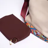 Bolso tipo hobo color beige con detalles en marrón. Tiene correa de mano marrón y correa bandolera ancha de tela estampada multicolor. Incluye un monedero marrón con cierre.
