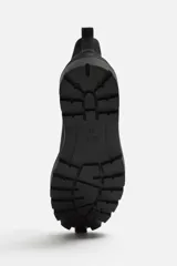 Bota Chelsea negra de cuero con acabado serraje, caña baja, puntera redondeada, tirador trasero y suela track con volumen.