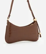 Cartera baguette color blanco con textura croco, correa de hombro con esferas plateadas y cierre de cremallera.