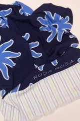 Pareo rectangular de viscosa con estampado de flores rojas sobre fondo borgoña y borde inferior con rayas verticales rojas, amarillas y blancas.