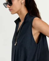 Vestido evasé sin mangas confeccionado en denim liviano, con cuello mao y falsa cartera que forma un escote en V con tabla central delantera. Posee bolsillos laterales, tablón en el centro de la espalda y ruedo redondeado con tajos laterales. Largo hasta mitad de la pantorrilla.