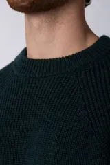 Sweater marrón de punto con cuello redondo y mangas largas raglán. Tejido grueso con textura acanalada. Corte holgado.