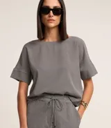Blusa de crepé con estampado geométrico en blanco y negro, escote redondo y mangas cortas con detalle de doblez.