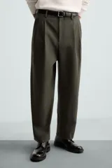 Pantalón verde oliva de corte amplio con pliegues en la parte delantera, bolsillos laterales y traseros de ojal.
