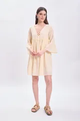 Vestido corto amarillo con escote en V con cordones y mangas 3/4 acampanadas.