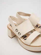 Sandalias de cuero color crema con plataforma, taco cuadrado y tiras anchas con argollas metálicas.