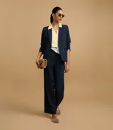Pantalón de vestir azul marino, de corte recto, con bolsillos laterales y traseros. Se ajusta a la cintura con cinturón de cuero marrón.
