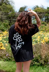 Remerón negro de corte amplio con estampa de flor blanca en la espalda.