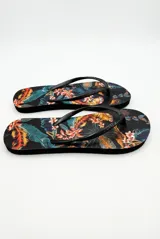 Ojotas negras con estampa tropical de hojas y flores en tonos naranja, amarillo y verde azulado.