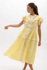 Vestido midi amarillo de lino, con volados en las mangas y detalle de volados y botones a lo largo del frente. Presenta un corte con talle marcado y falda escalonada.