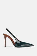 Zapato tipo slingback de tacón alto y fino, con punta afilada. El cuerpo del zapato es de charol verde oscuro, mientras que el tacón y el borde del talón son de color marrón.