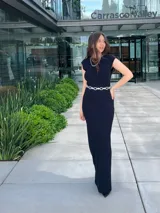 Vestido largo negro de corte ajustado, con cuello redondo y mangas cortas. Incluye cinturón plateado de eslabones.