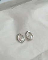Par de aros de plata 950 con diseño orgánico o irregular, cada uno engarzando una perla blanca en el centro.