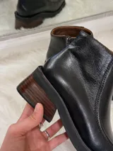 Botas de cuero negras con punta cuadrada, taco bajo de madera y cierre lateral.