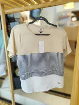 Remera de maternidad color beige con mangas cortas y corte holgado. Presenta un panel horizontal a rayas grises y un sistema de apertura horizontal con telas cruzadas por debajo.